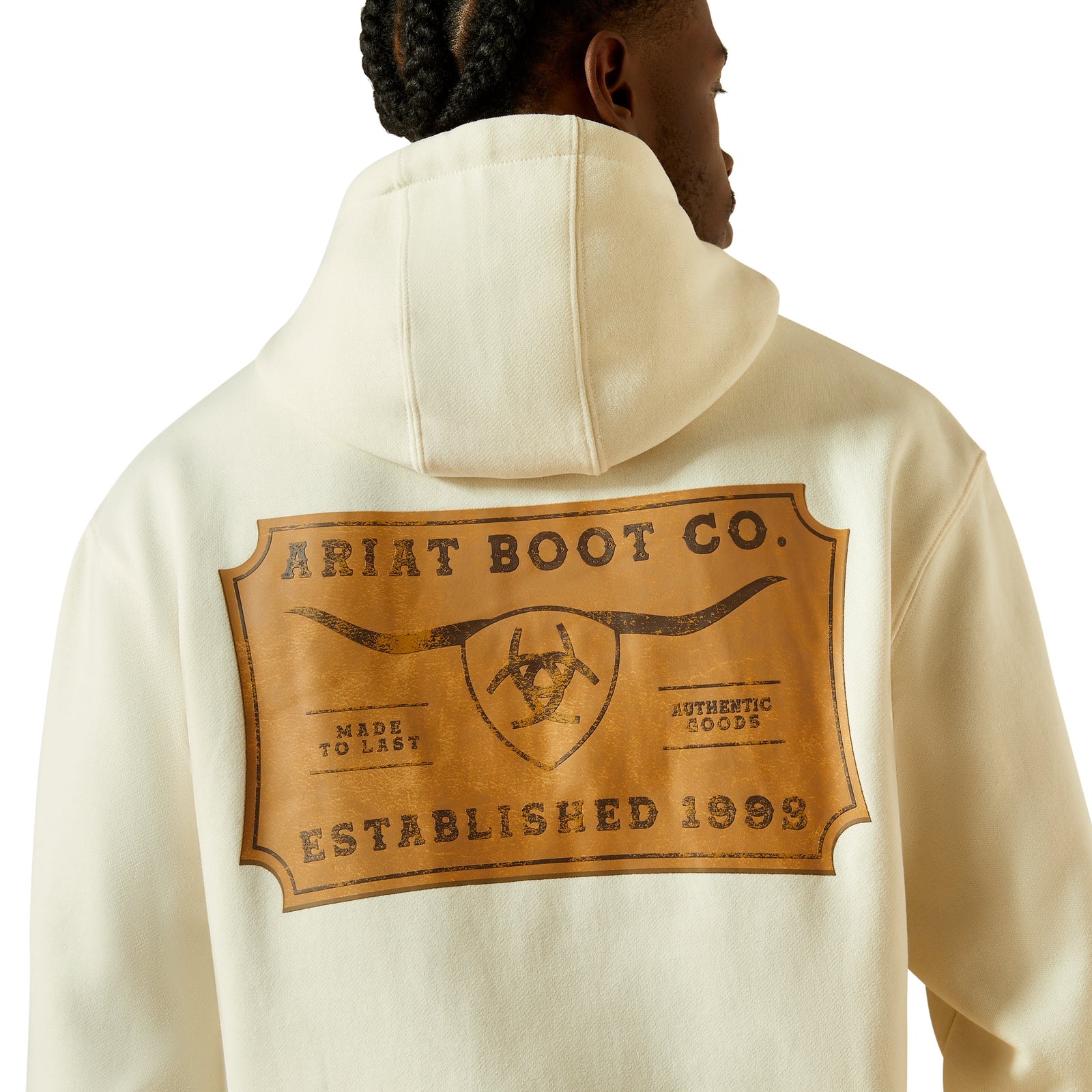 Person wearing a cream hoodie with Ariat Boot Co. logo on the back
