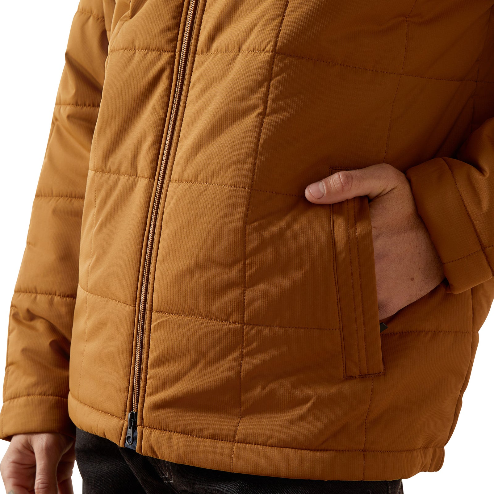 Close-up of a person wearing a brown quilted jacket with a hand in a pocket.