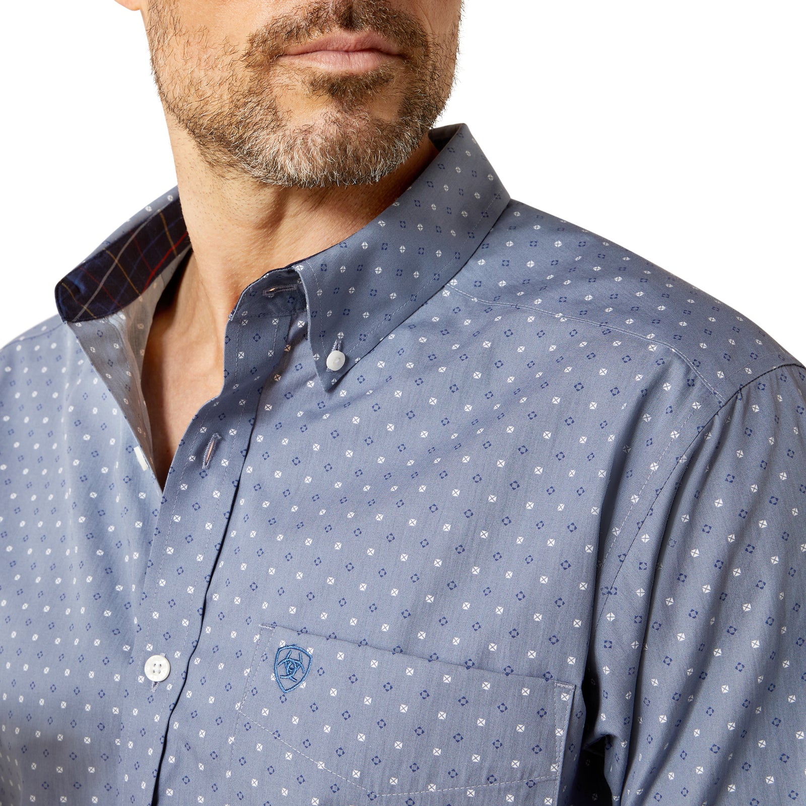 Close-up of a man wearing a patterned shirt with a visible brand logo.