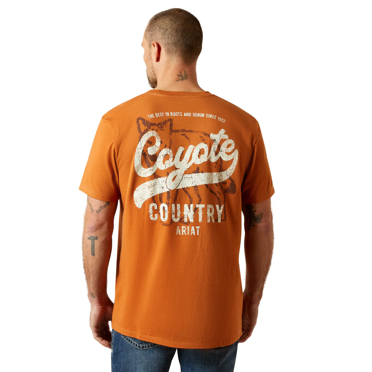 Man wearing an orange 'Coyote Country' Ariat t-shirt on a white background