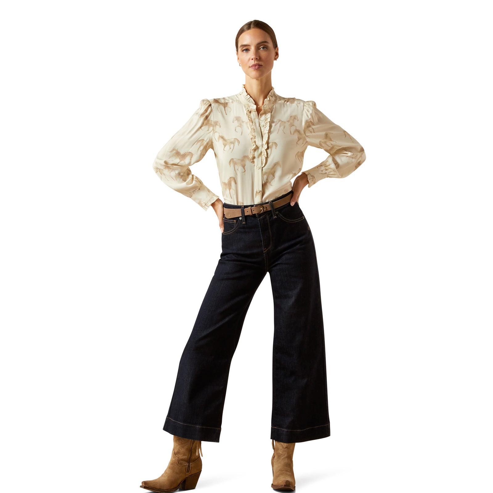 Woman wearing a beige patterned blouse and dark jeans on a white background