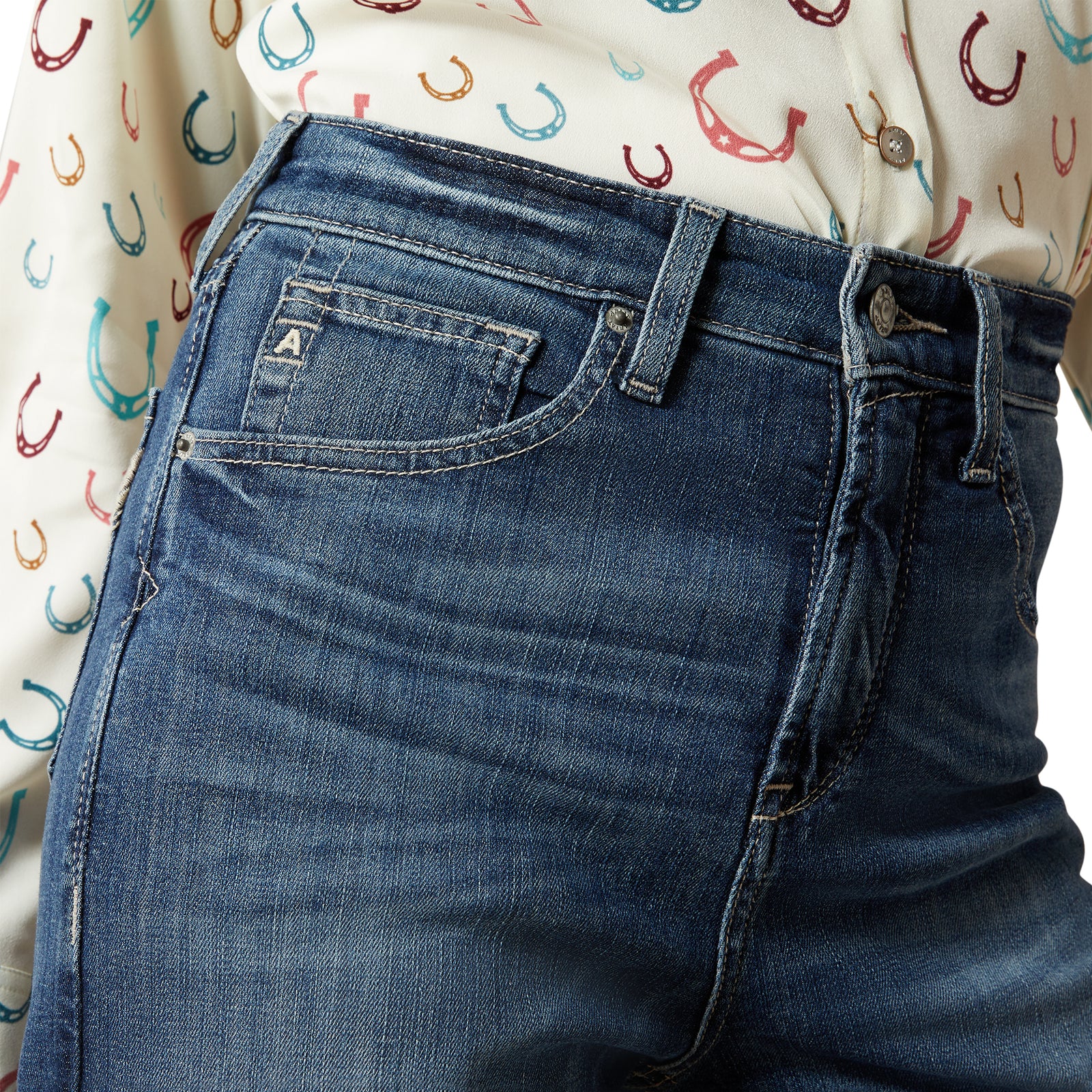 Ariat Women's Rosalie Ultra High Rise Wide Leg Jean. Close-up of blue jeans with a patterned shirt in the background