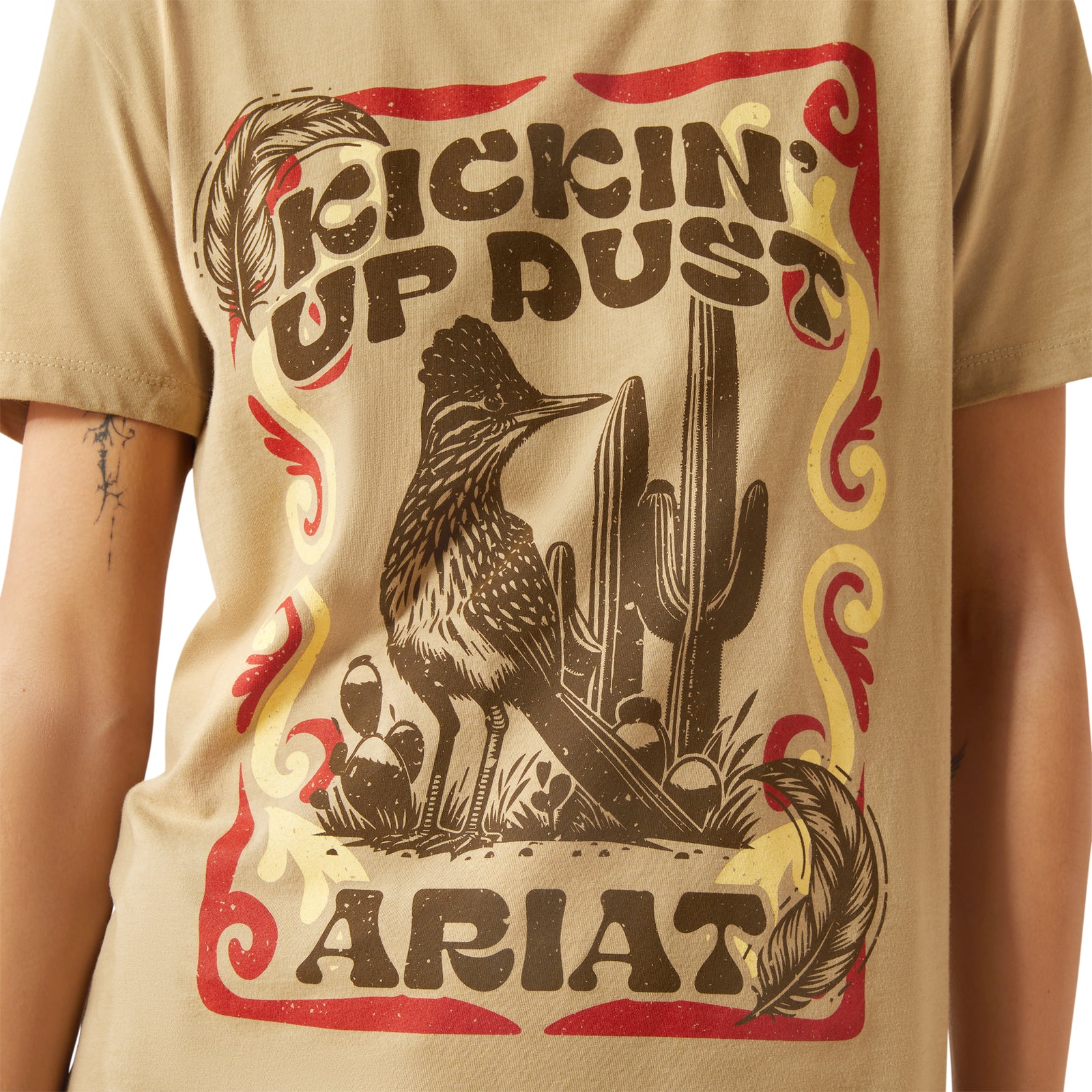 Ariat Women's Kickin Up Dust T-Shirt. Beige t-shirt with 'Kicking Up Dust' and Ariat graphic design.