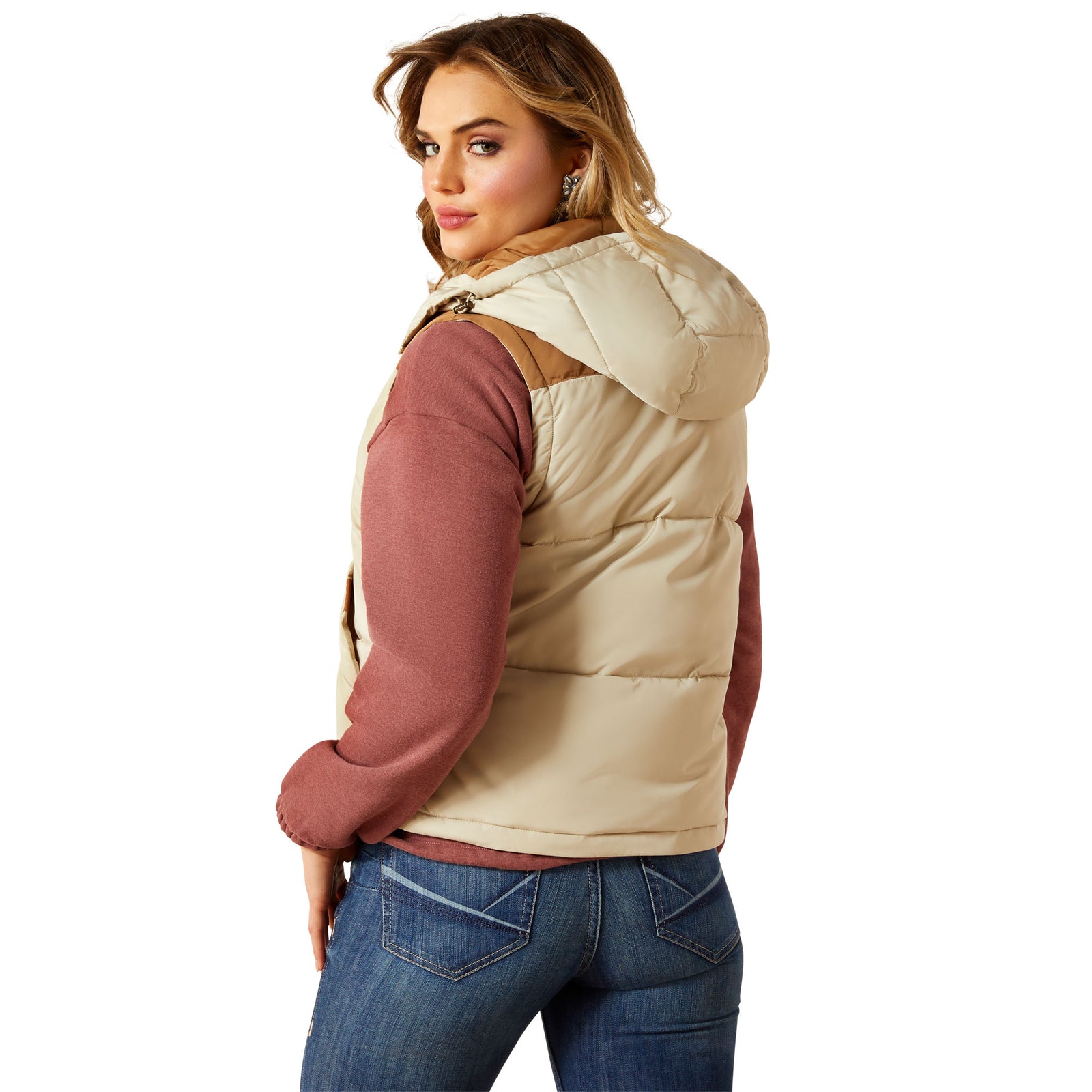 Woman wearing a beige puffer vest over a maroon long-sleeve shirt on a white background