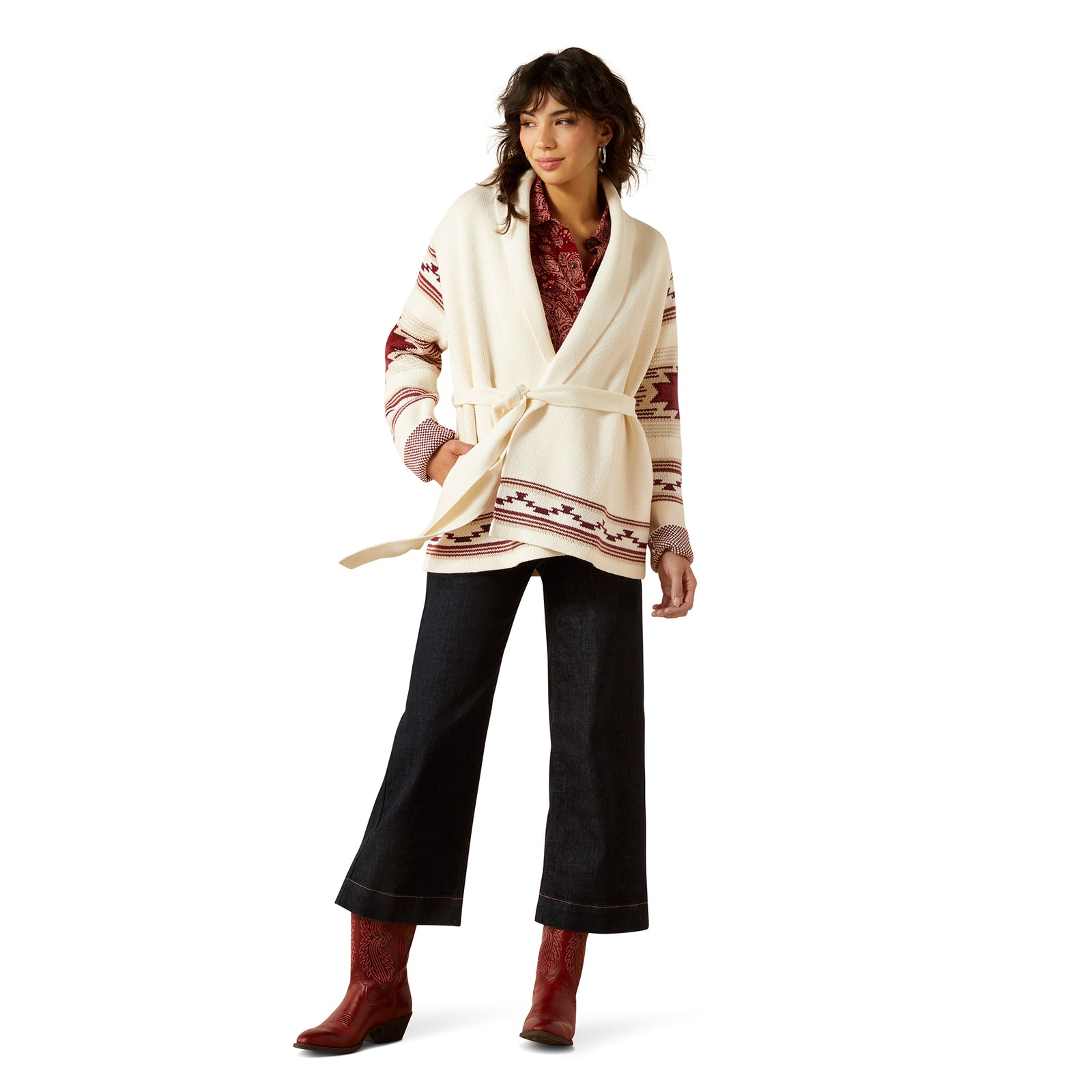Woman wearing a patterned cardigan, black pants, and red boots on a white background