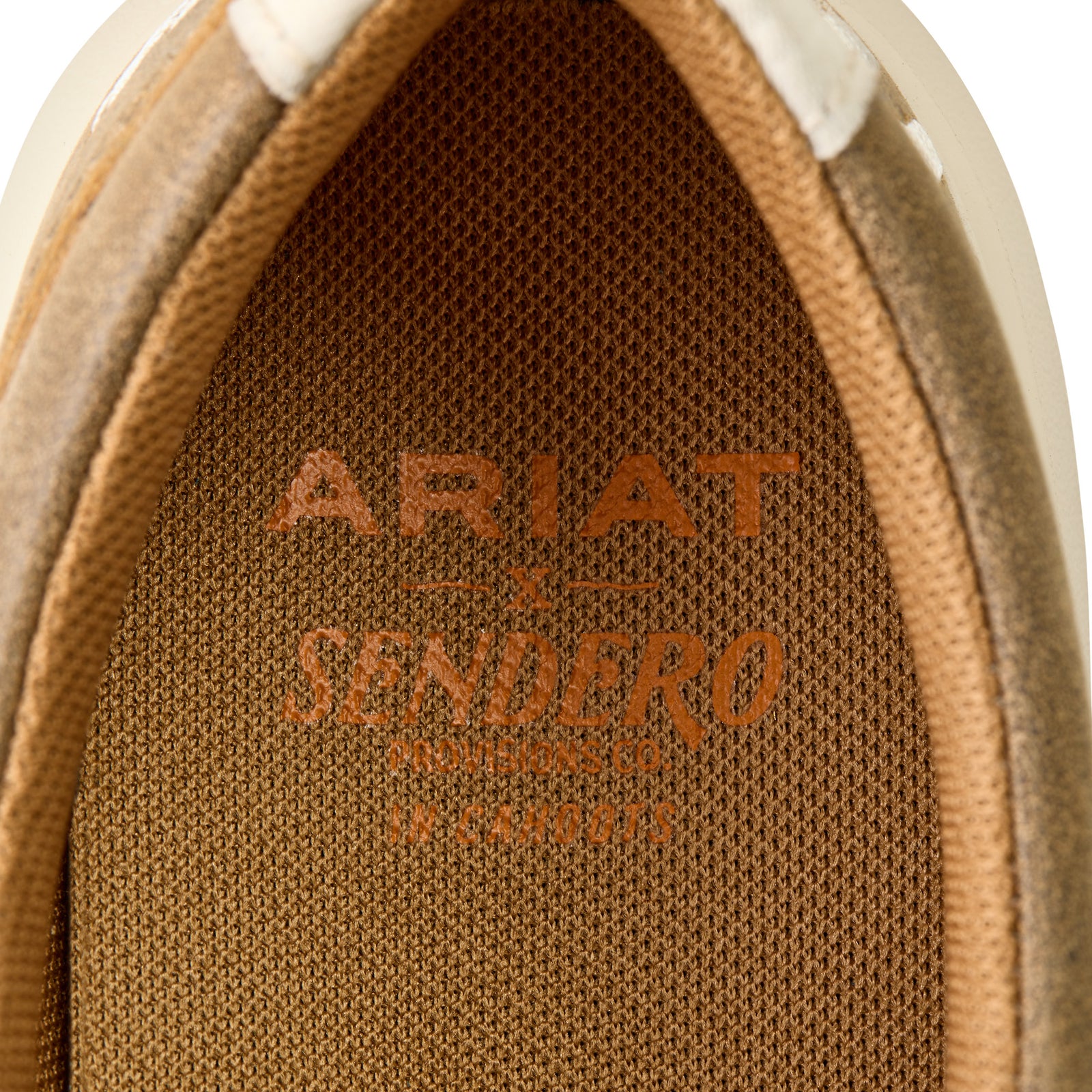 Ariat Women's Hilo Sendero Slip On Shoe. Close-up of Ariat Sendero logo on brown textured material