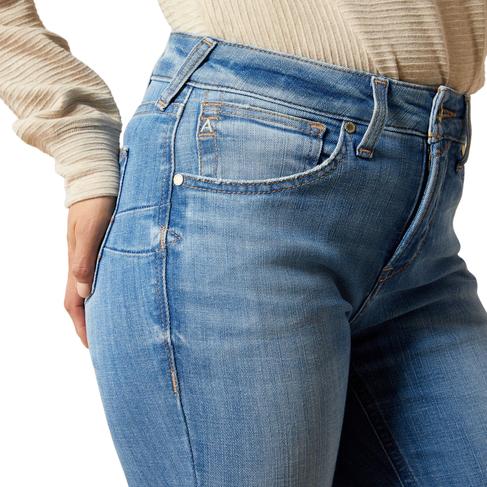 Close-up of blue jeans with a beige sweater on a white background
