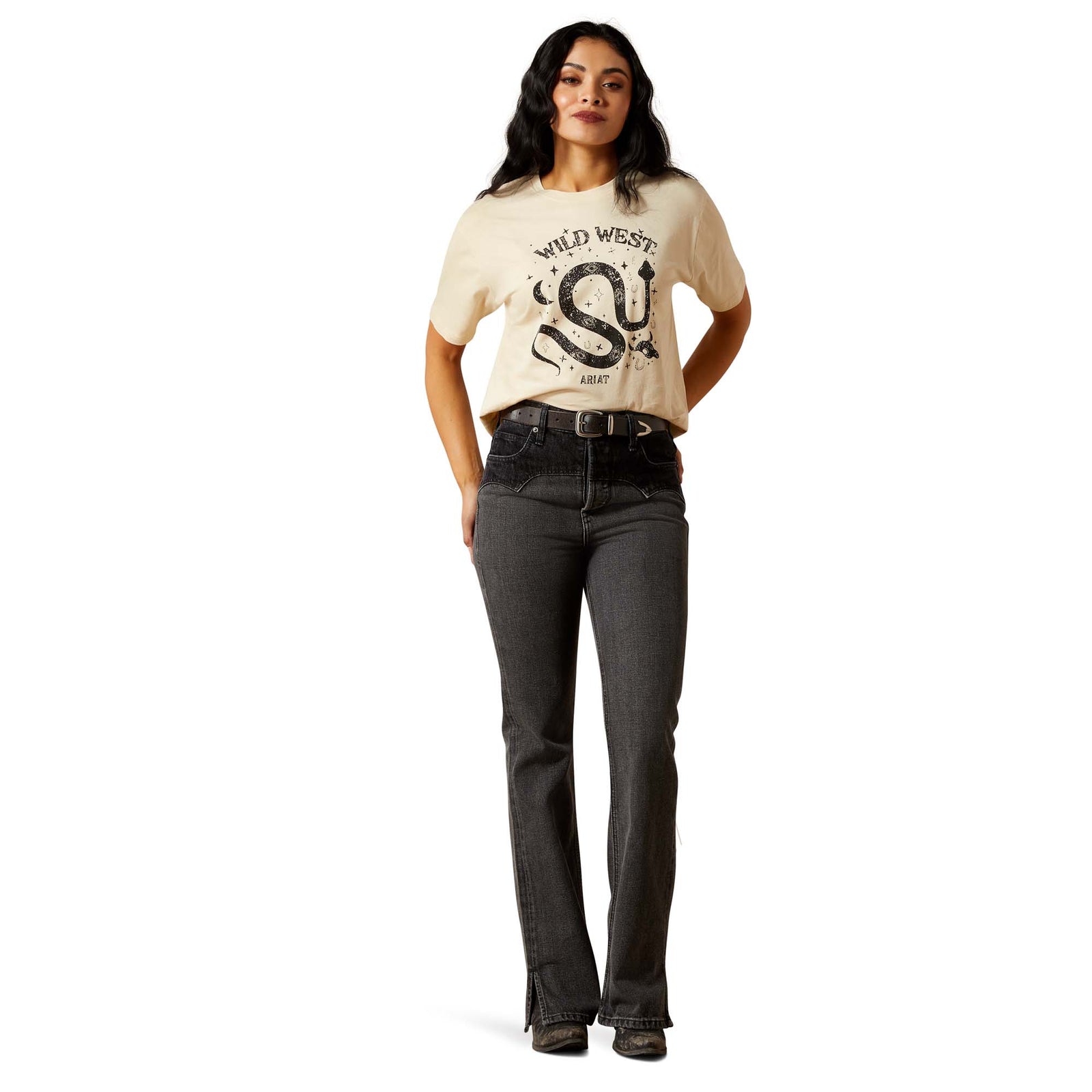 Woman wearing a beige t-shirt with 'Wild West' graphic and dark jeans on a white background