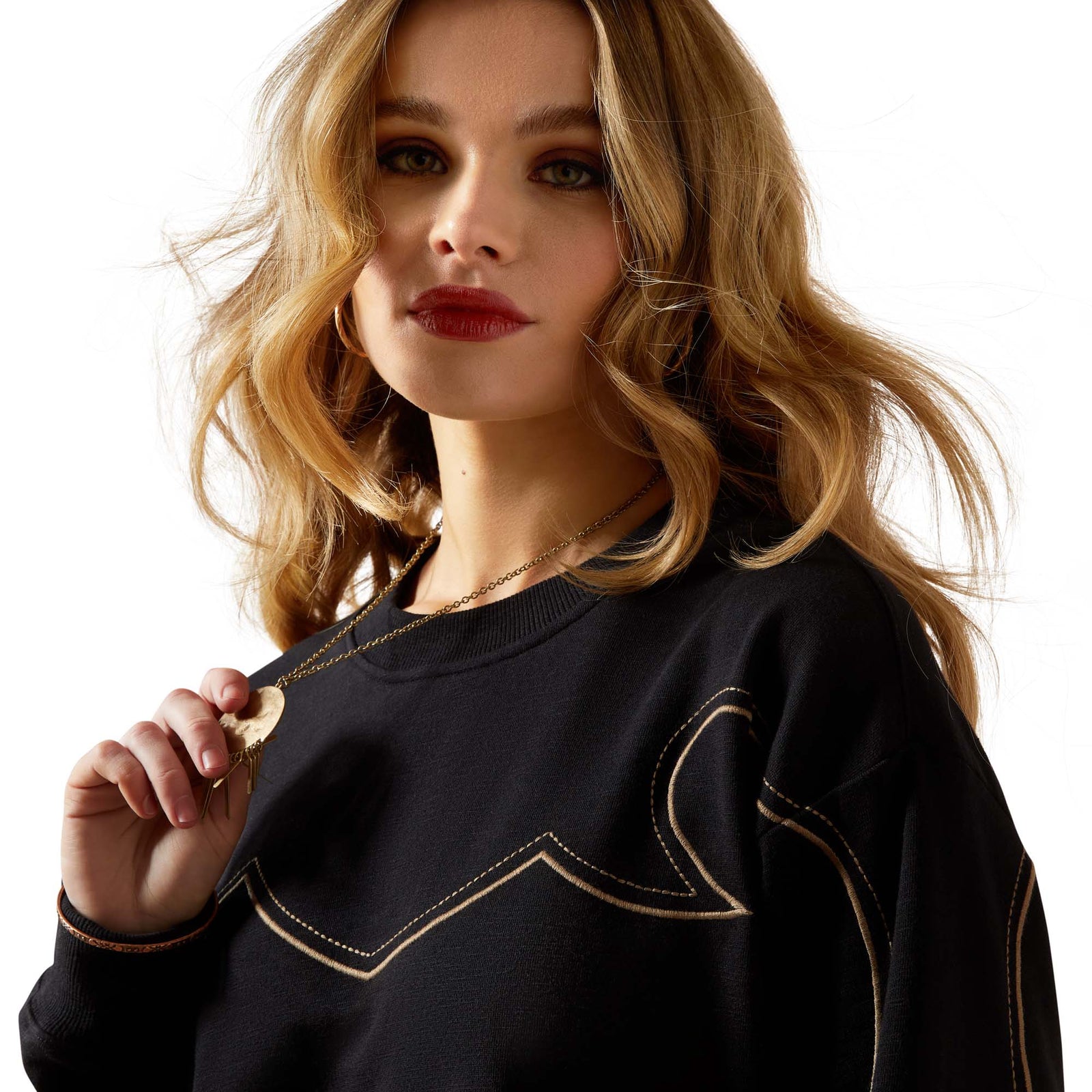 Woman wearing a black sweater with decorative stitching on a beige background