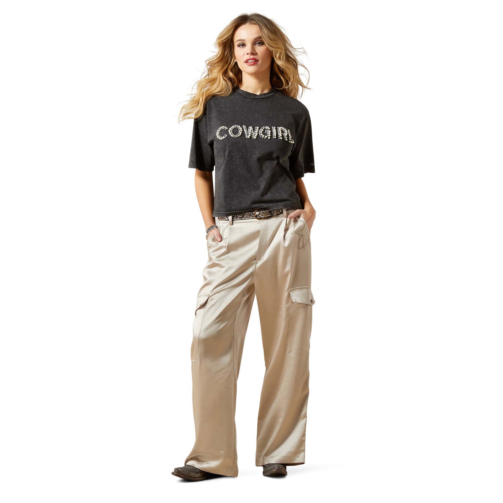 Woman wearing a black 'COWGIRL' t-shirt and beige pants on a white background