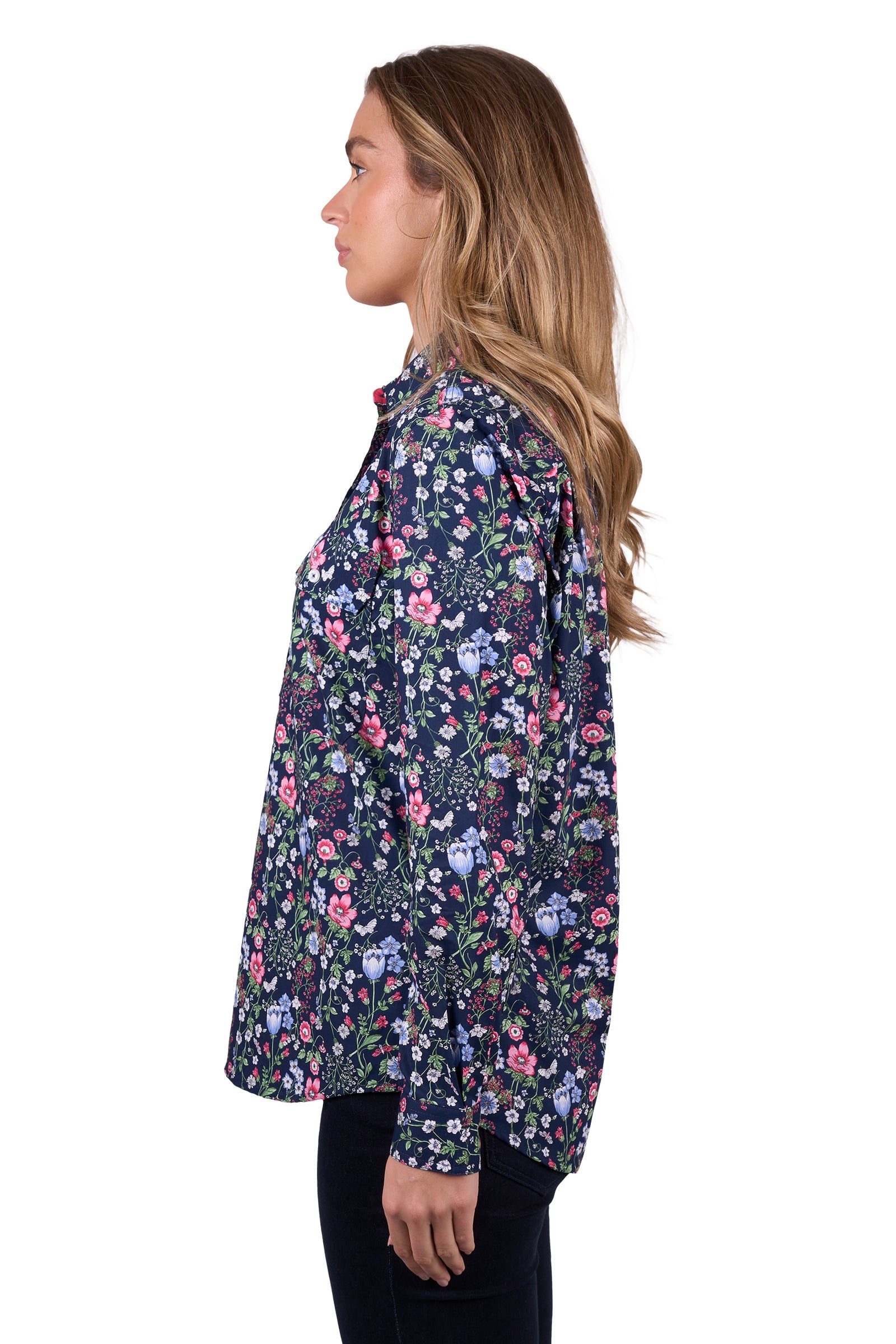 Hard Slog Women's Raya 1/2 Placket L/S Shirt. A woman wearing a long sleeve floral shirt with a half placket and two pockets, the shirt has contrast inside collar stand and sleeve cuffs, and logo buttons.