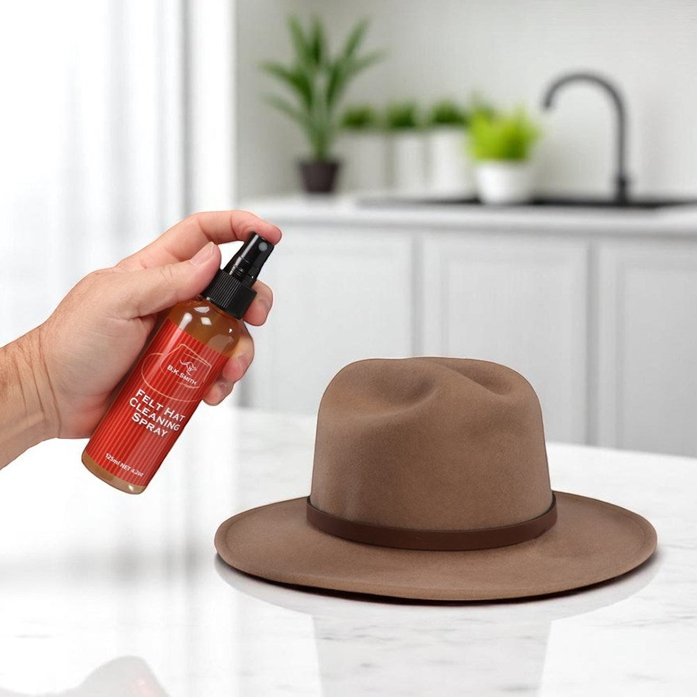 B.K. Smith Felt Hat Care Kit. Person holding a bottle of felt hat care spray next to a brown hat on a white surface.