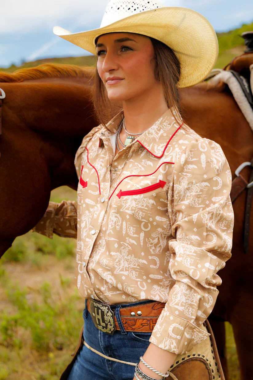 Woman in cowboy hat and patterned shirt standing next to a horse in an outdoor setting