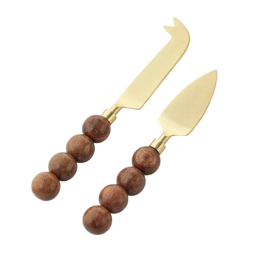 Two cheese knives with wooden bead handles on a light gray background