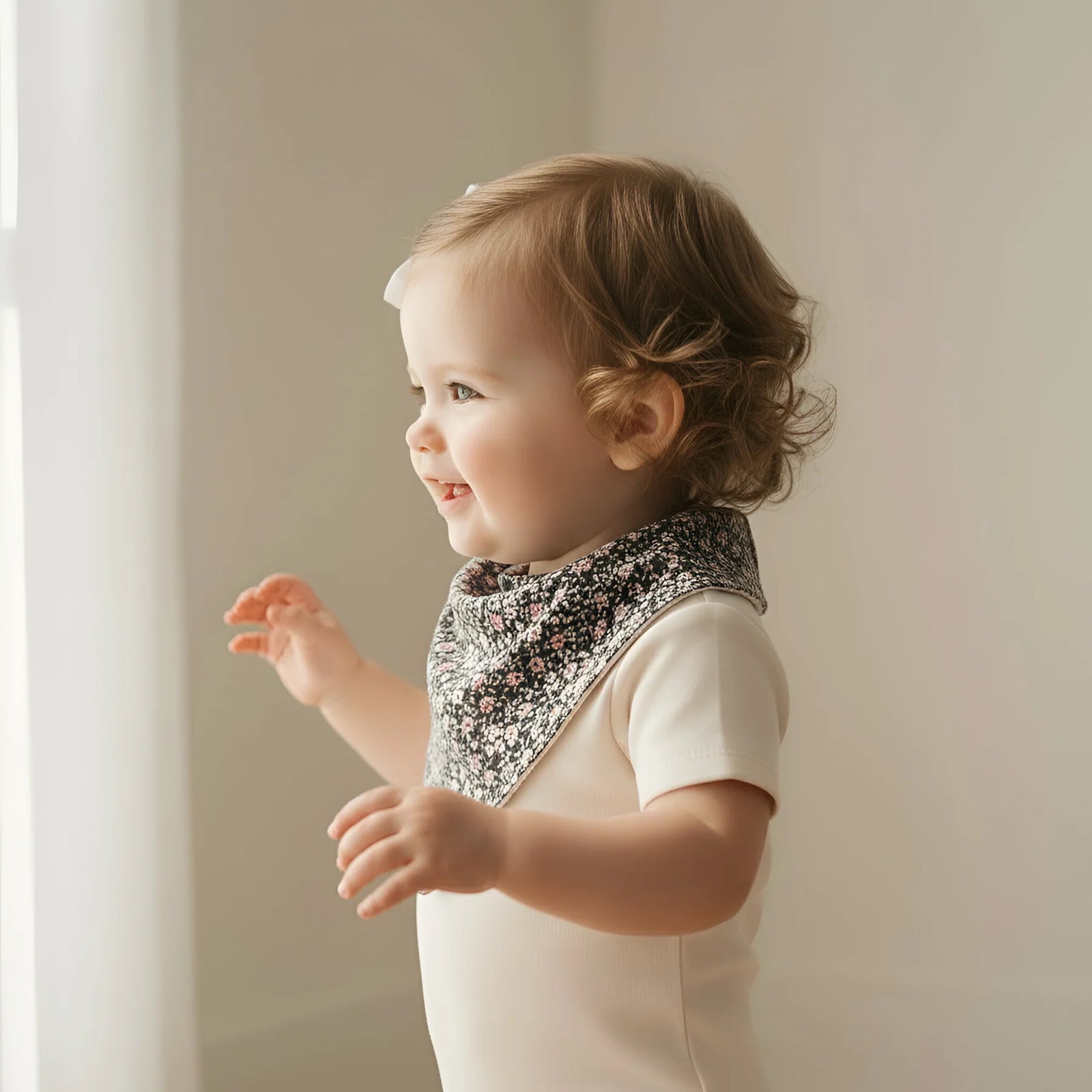 Baby wearing a floral bib against a neutral background