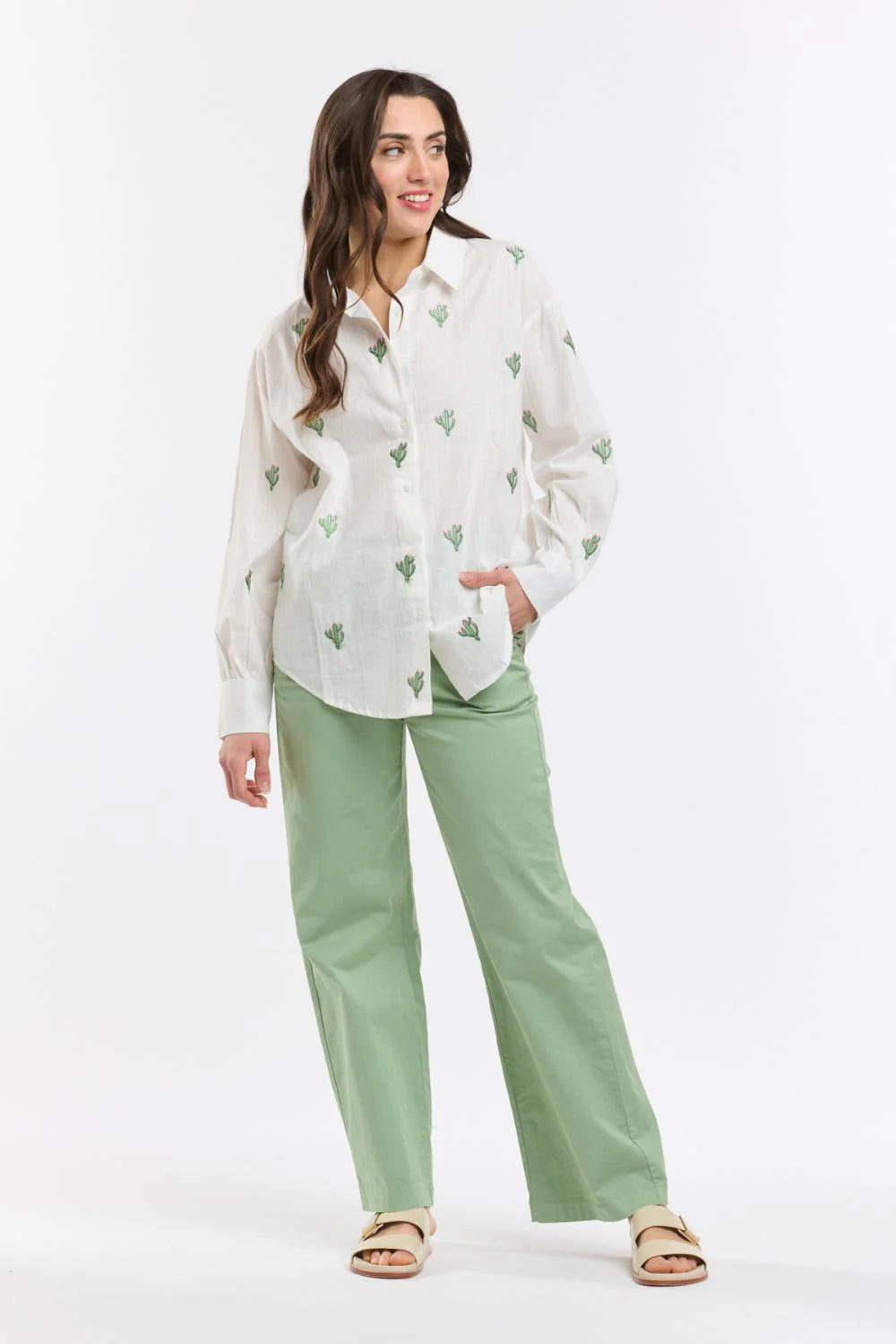 Italian Star Women's Cactus L/S Shirt. Woman wearing a white blouse with green patterns and green pants on a white background