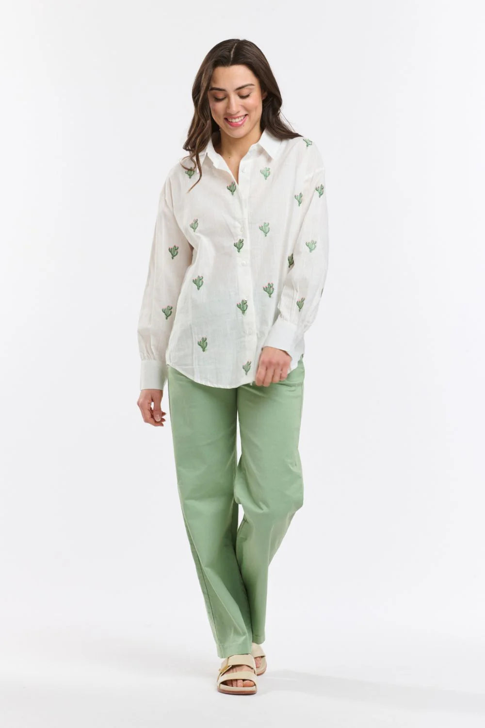Italian Star Women's Cactus L/S Shirt. Woman wearing a white blouse with green patterns and green pants on a white background
