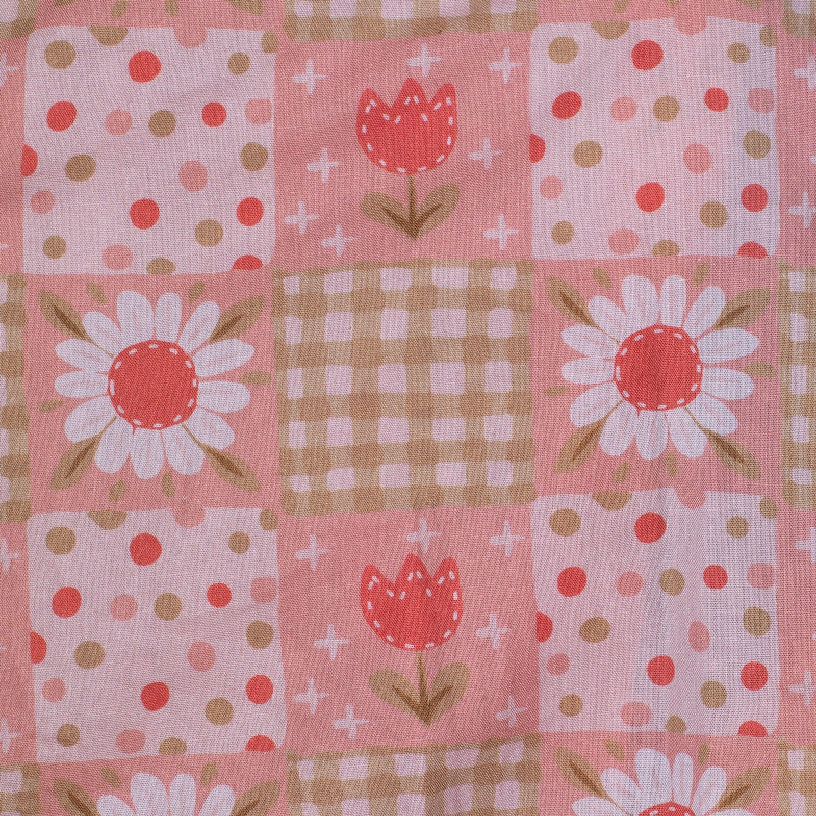 Patchwork fabric with floral and geometric patterns on a pink background