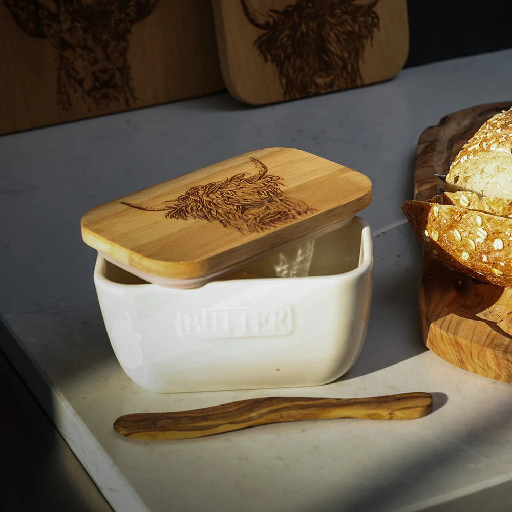 White container with wooden lid and spoon on a stone surface with bread in the background