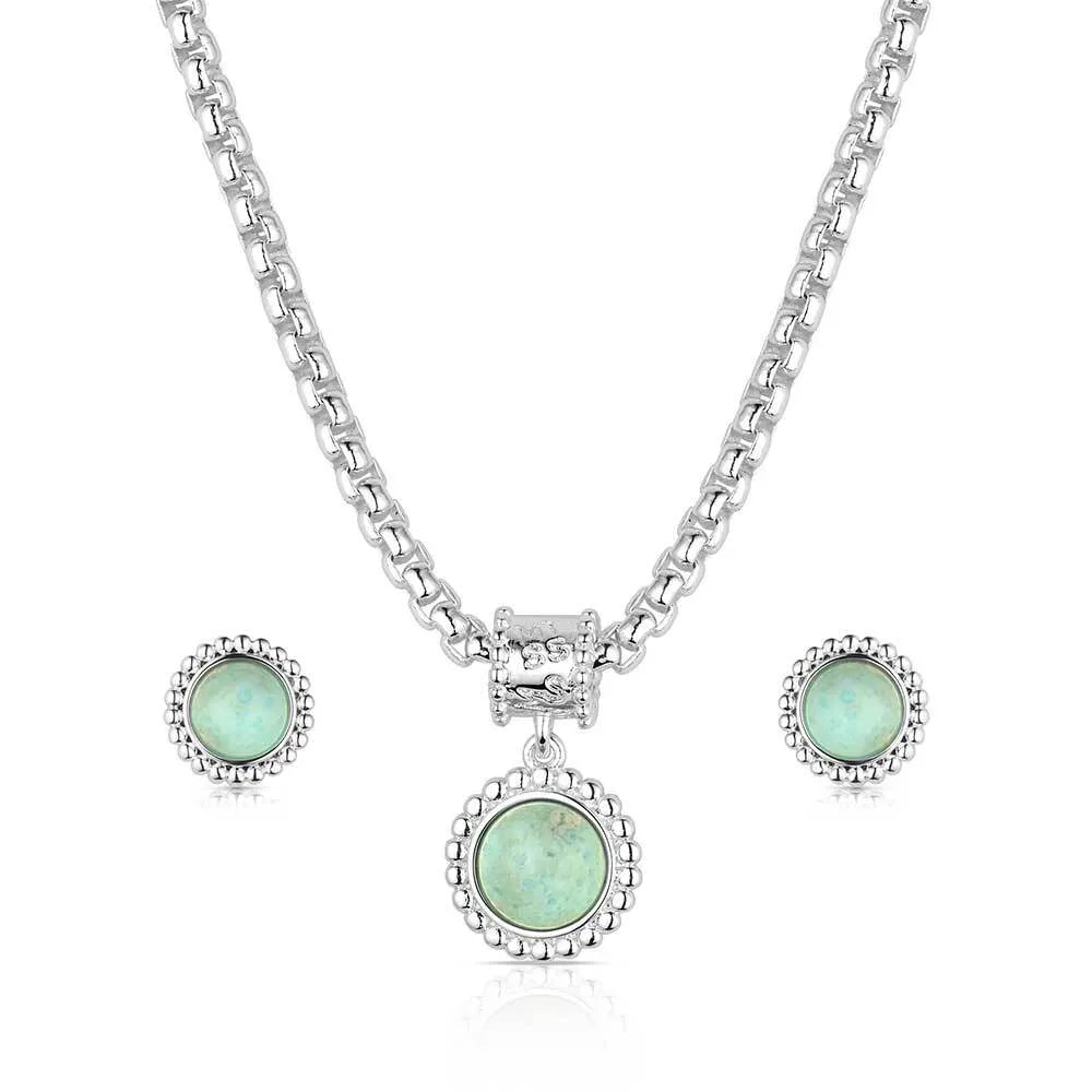 Jewelry set with green gemstones and silver chains on a white background