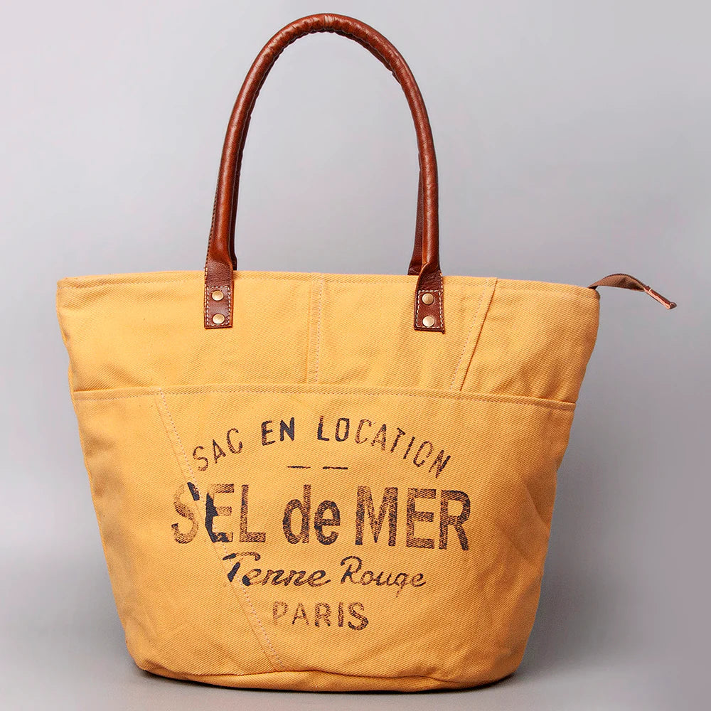American Darling Upcylced Canvas Weekender Bag. Yellow tote bag with brown handles and text on a gray background