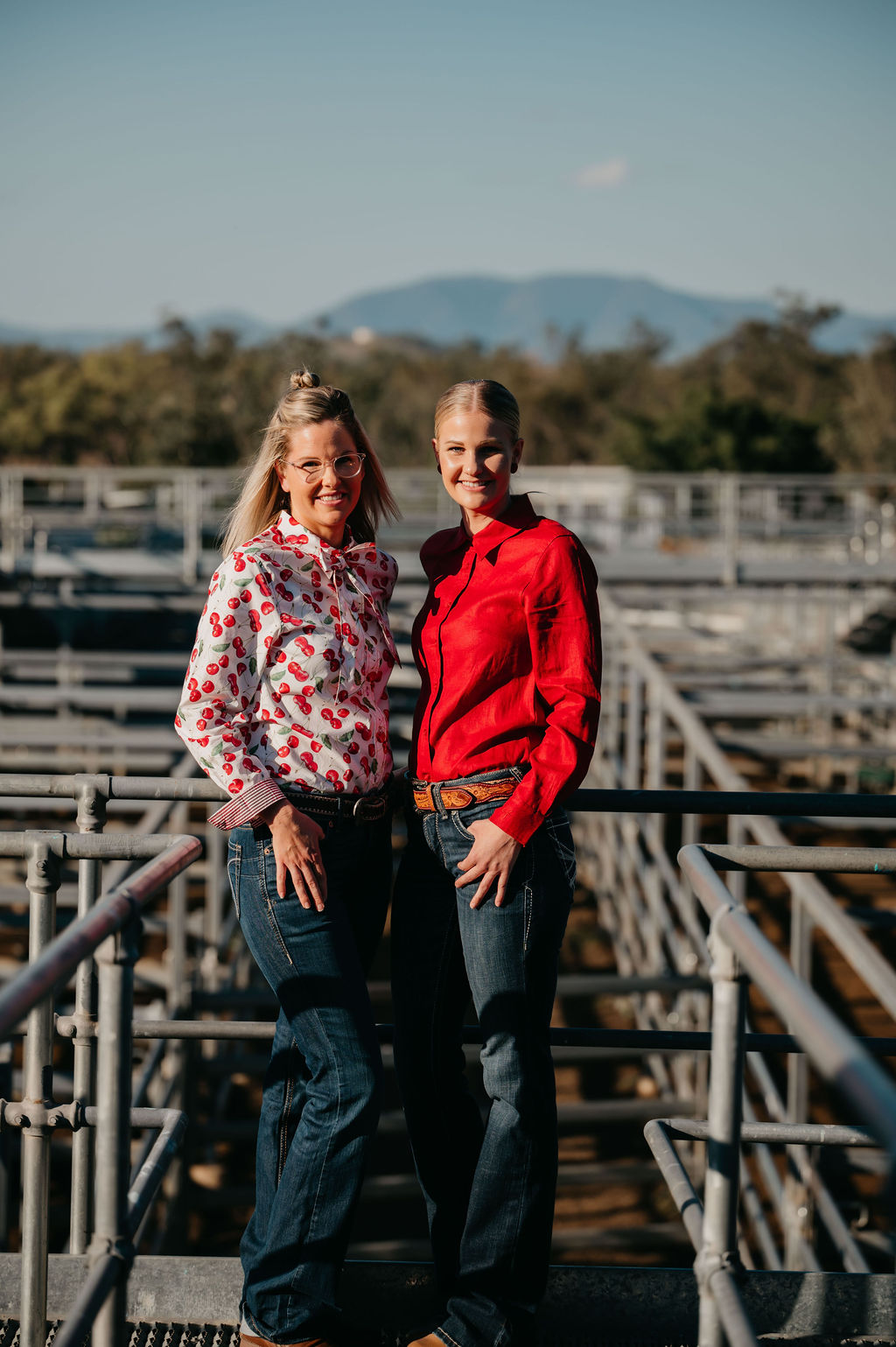 Two women standing on metal bleachers with a scenic background