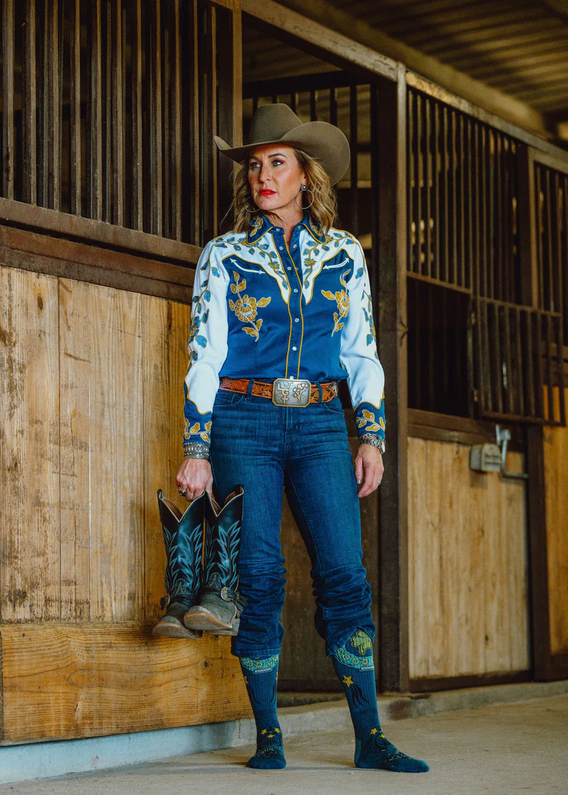 Lucky Chuck Fringe Lucky Horseshoe Performance Socks. Woman in cowboy attire standing in a stable