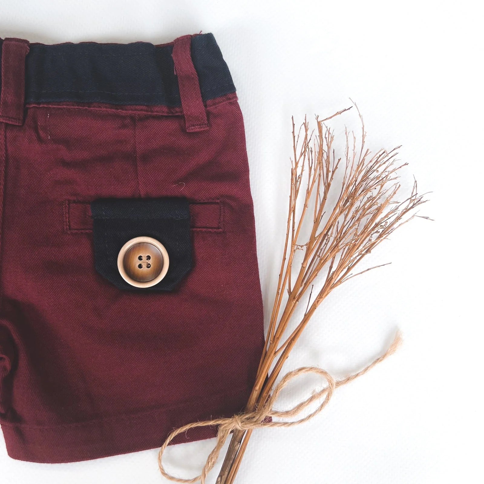 Love Henry Infant Boy's Oscar Shorts. A pair of maroon infant boy's shorts with a belt, button fastening, and pockets, accompanied by a pair of brown shoes.