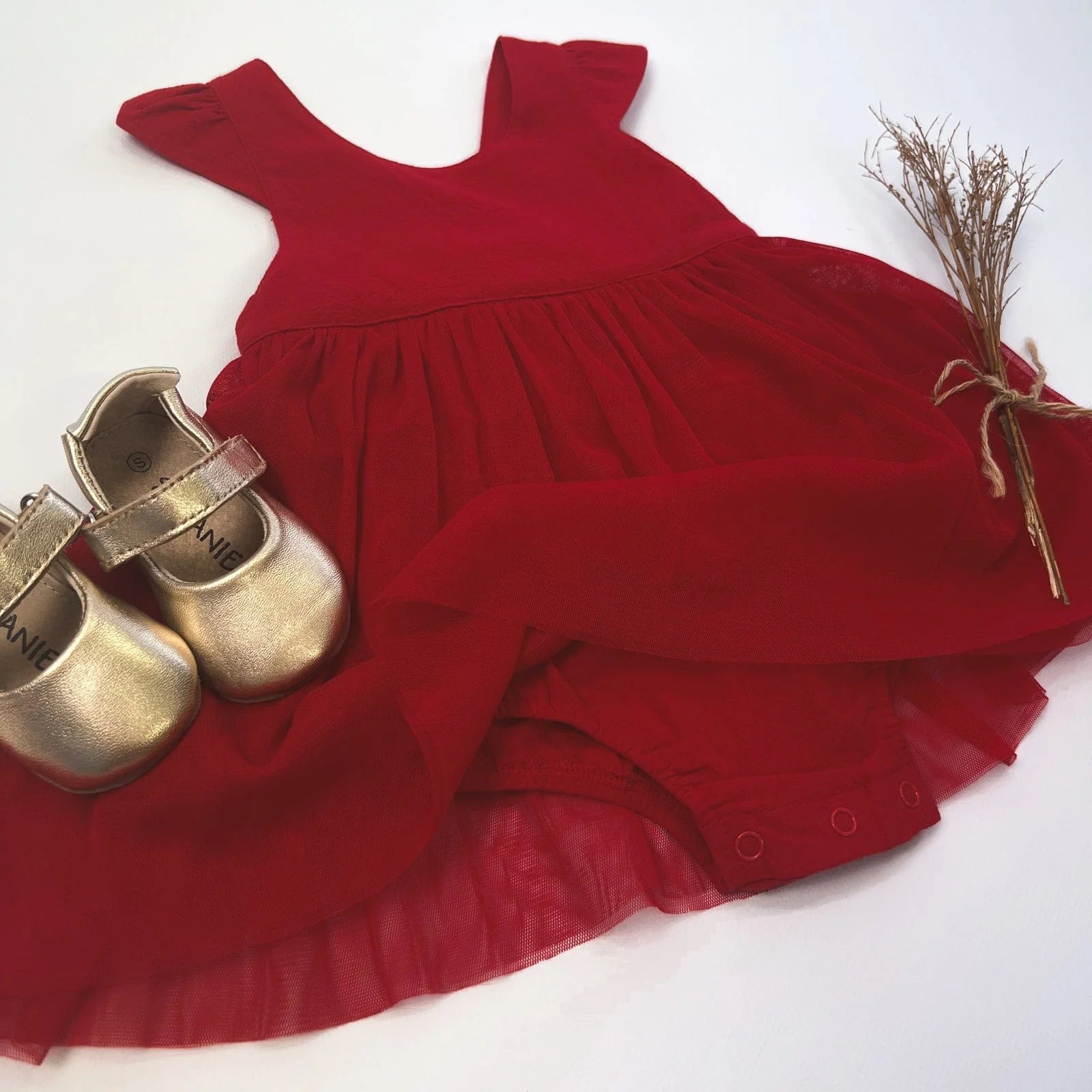 Love Henry Infant Girl's Lottie Dress. A red infant girl's dress with a pleated waist and sleeveless design, accompanied by a pair of shoes and a small decorative bow.