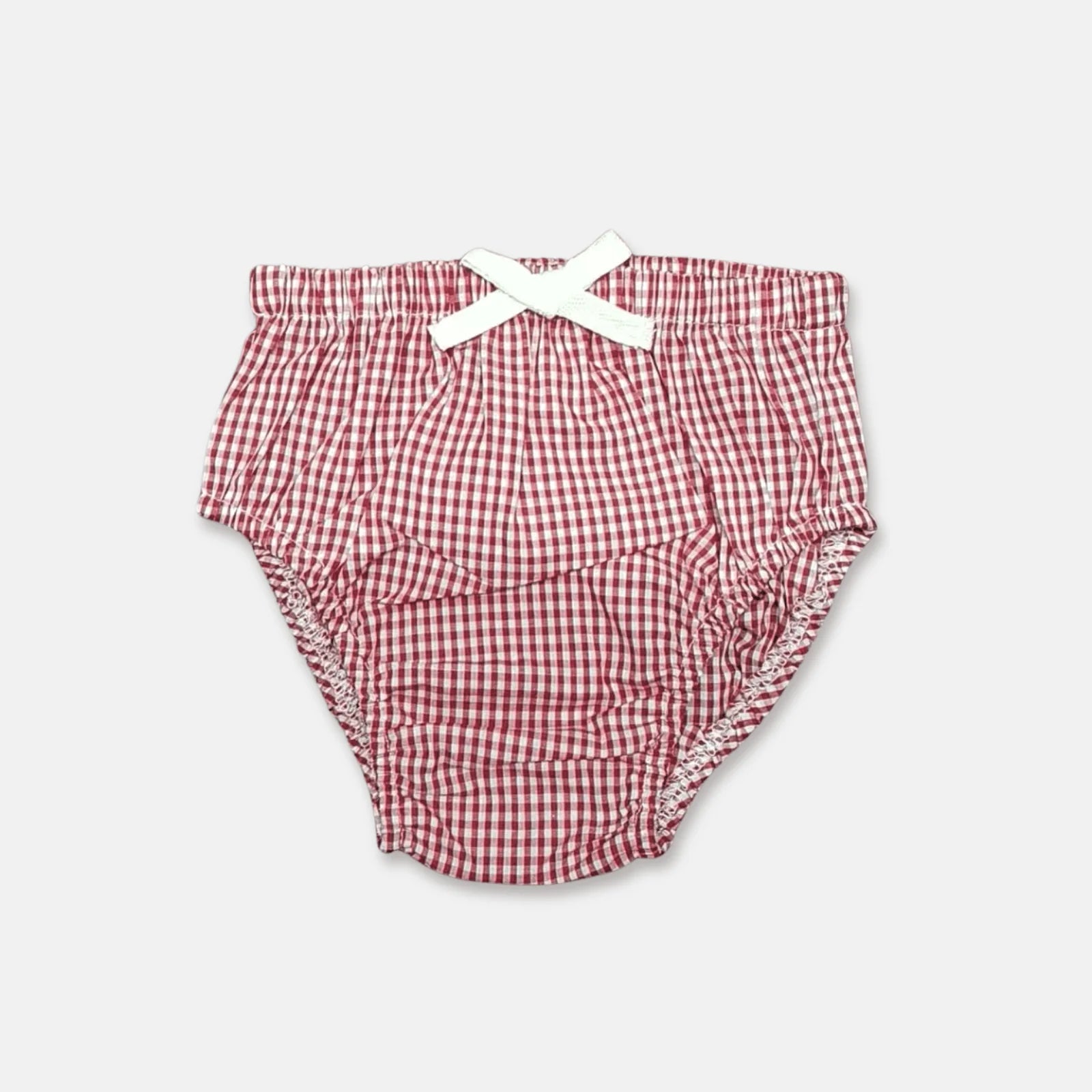 Love Henry Infant Girl's Pilcher. A red and white checkered infant girl's pilcher with a white bow on the front, made of cotton fabric.