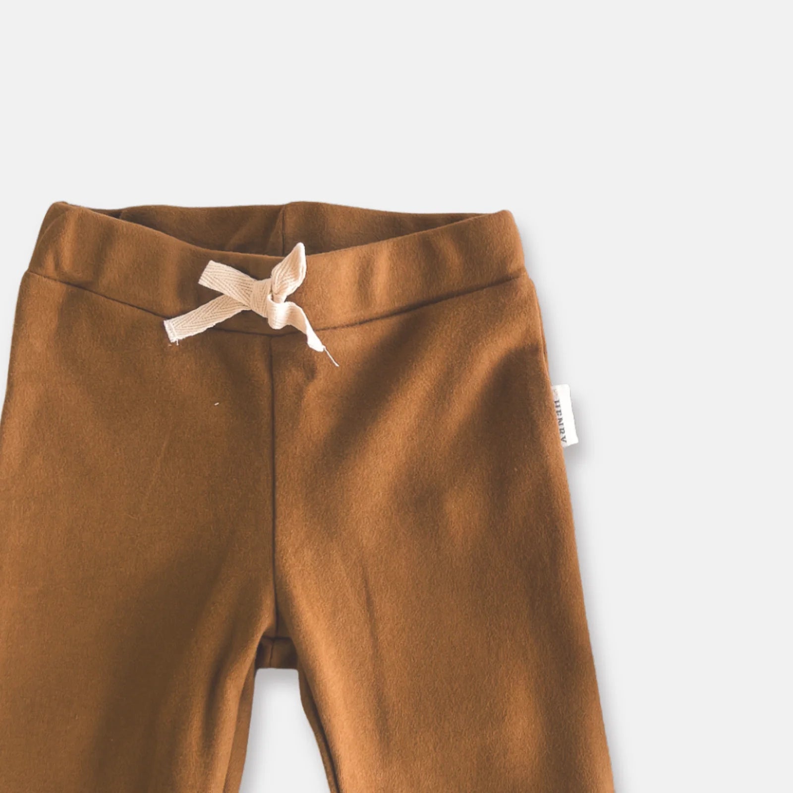 Love Henry Baby Boy's Comfy Pants. Brown pants with a drawstring and visible brand tag on a light gray background