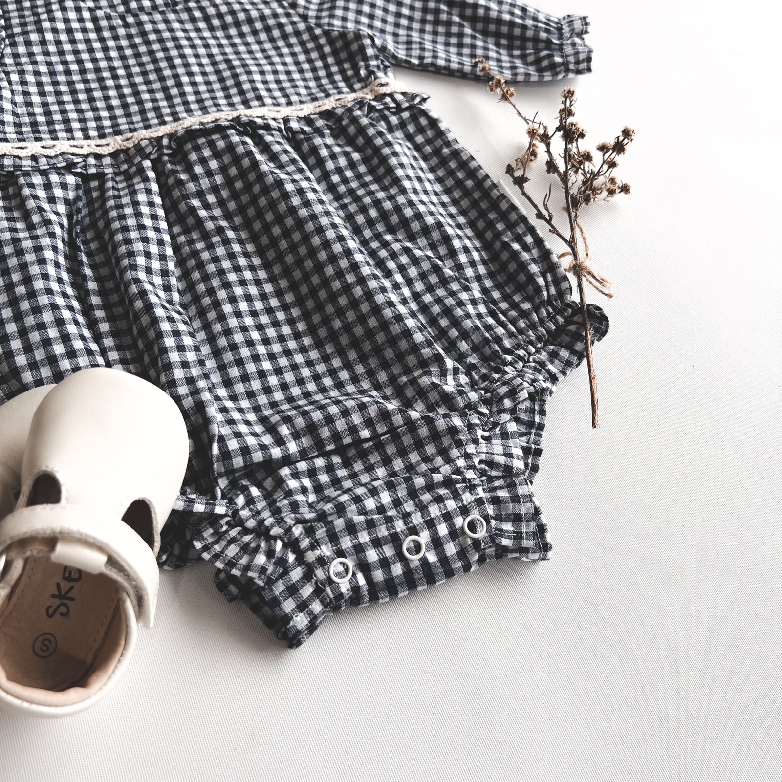 Love Henry Baby Girls L/S Nora Playsuit - Navy Check. Navy and white checkered romper with ruffled details on a light background