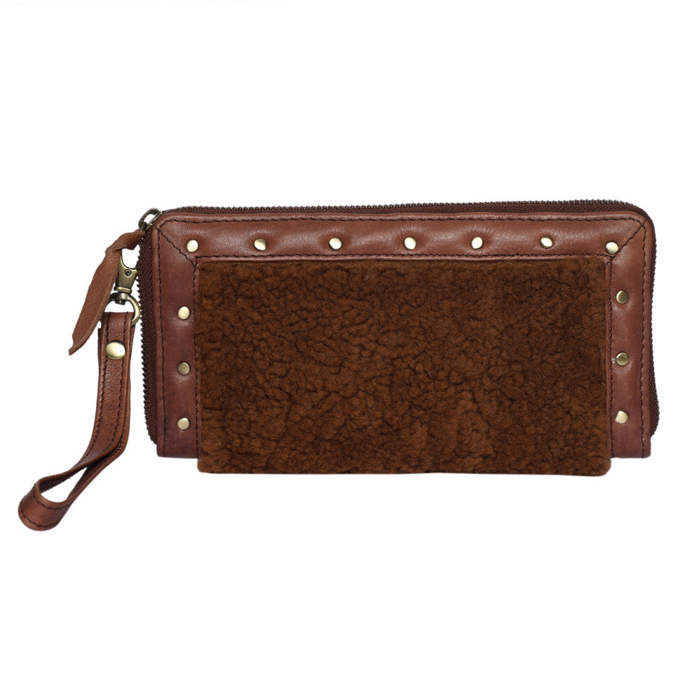 The Design Edge Women's Shearling Fur Clutch Wallet. A brown shearling fur clutch wallet with a leather wrist strap and stud work detailing, zipper closure, and a textured fur surface on one side.