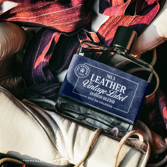 Perfume bottle labeled 'No. 3 Leather Vintage Label' on a textured surface with leather accents.