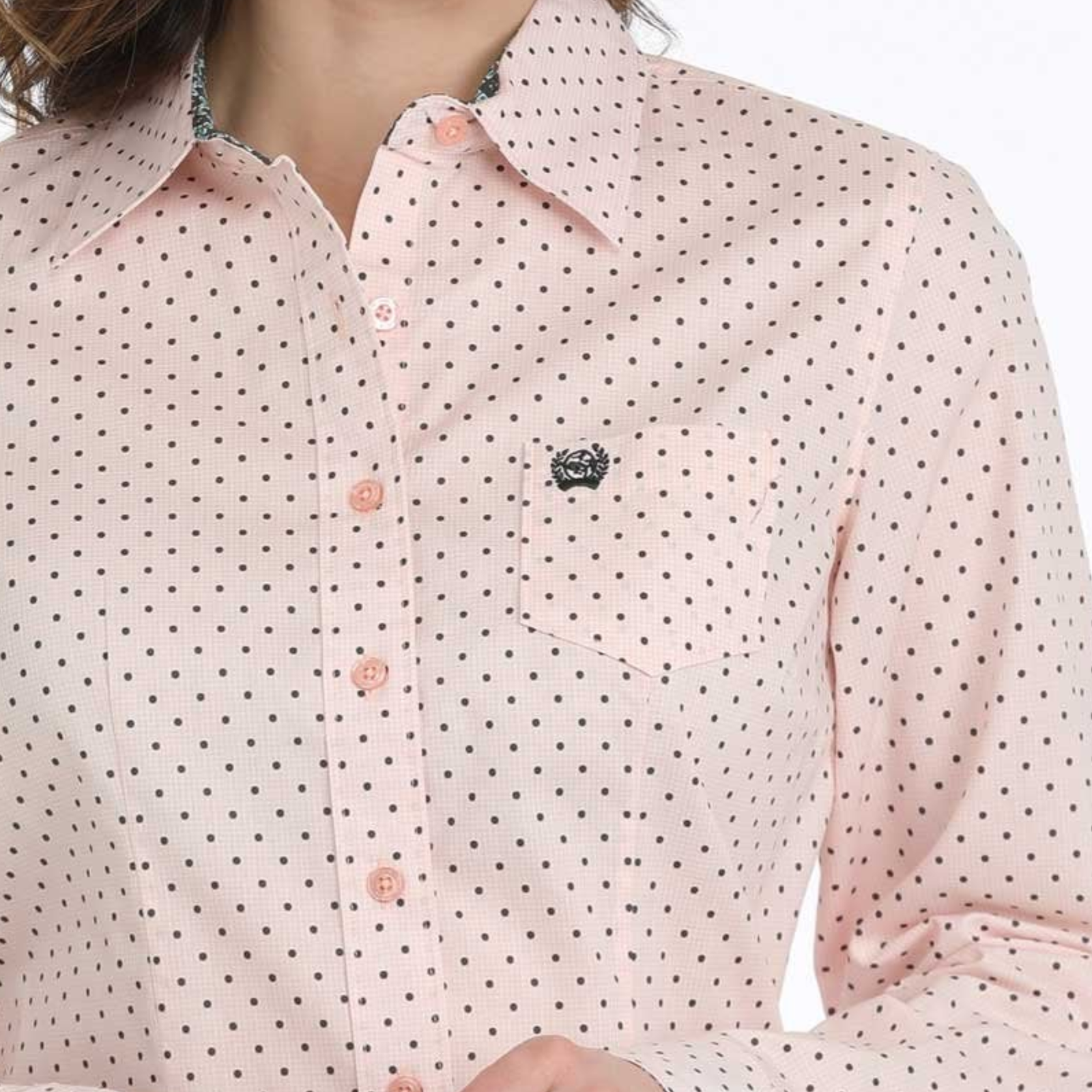 Close-up of a pink polka dot shirt with a brand logo on a white background