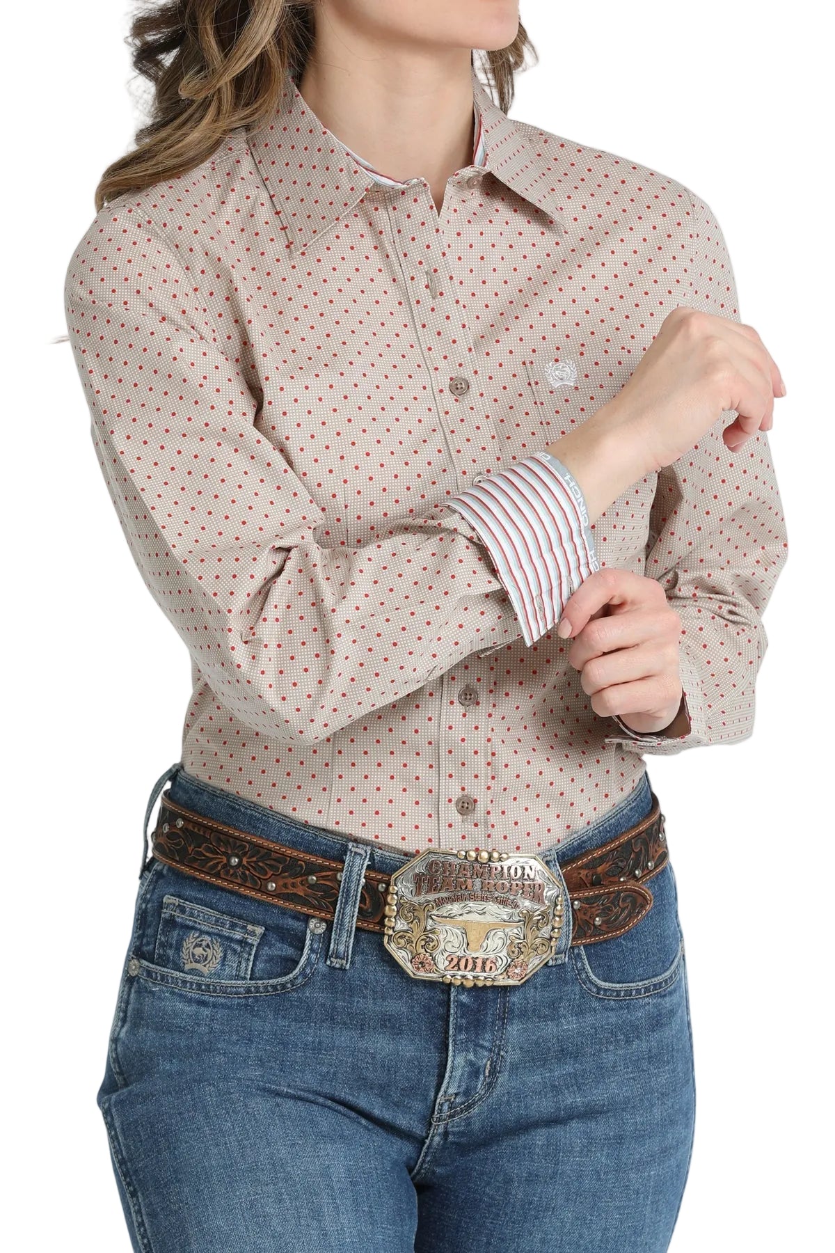 Woman wearing a patterned shirt and jeans with a belt and large buckle on a white background