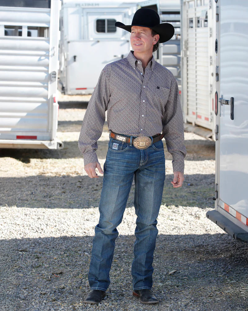 Man in cowboy hat and western attire standing in front of a trailer