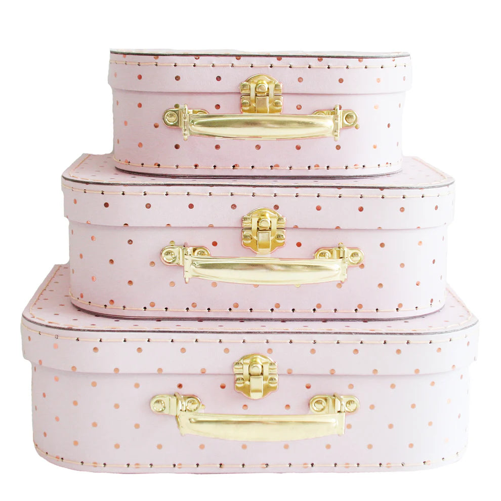 Set of three pink polka dot suitcases with gold handles on a white background