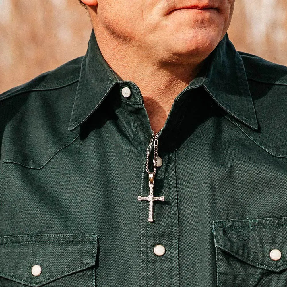 Man wearing a green shirt with a cross necklace against a blurred background
