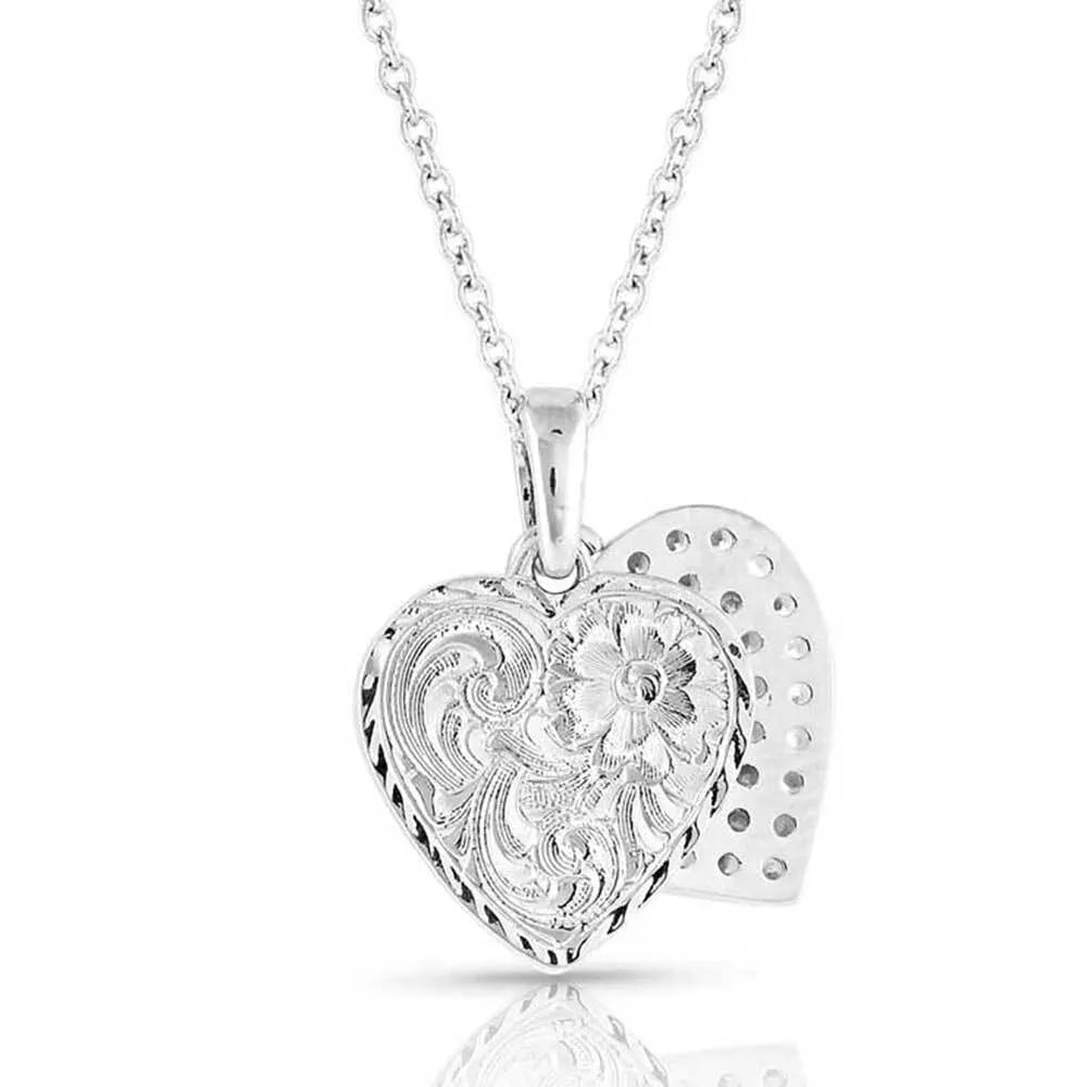 Montana Silversmiths Country Charm Crystal Love Necklace. Silver heart-shaped pendant with floral designs on a white background.