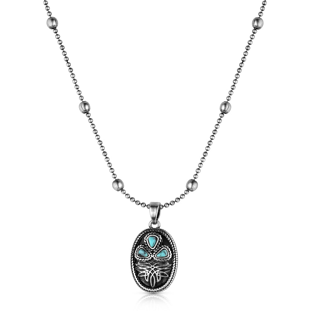 A silver-toned ball chain necklace with a decorative oval pendant featuring turquoise inlay and a stylized face design, shown on a plain white background.