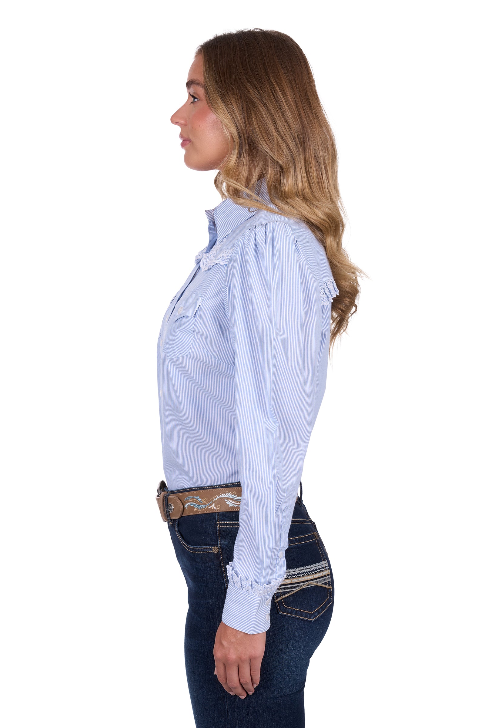 Pure Western Women's Lexi L/S Western Shirt. Woman wearing a light blue button-up shirt and dark jeans on a white background