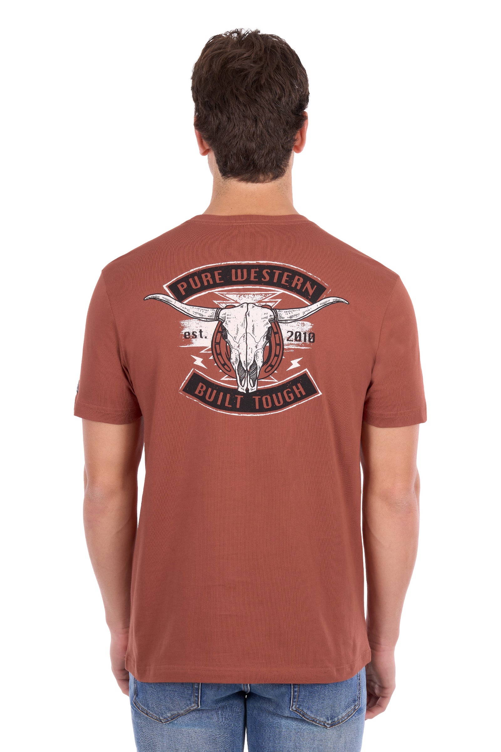 A man viewed from the back wearing a rust-colored t-shirt with a large graphic on the back featuring a steer skull and the text 'PURE WESTERN BUILT TOUGH'.