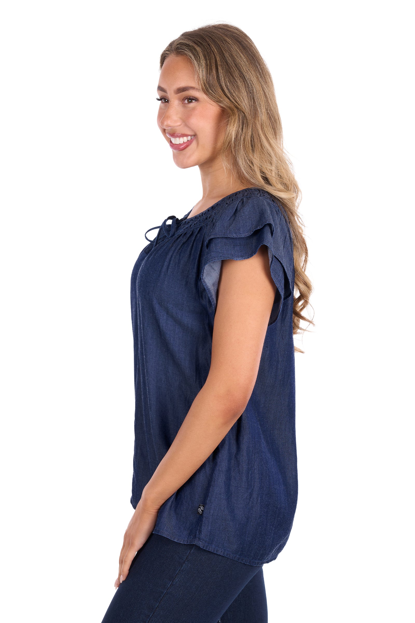 A woman modeling a navy blue short-sleeve top with ruffled cap sleeves and a tie detail at the neckline, shown from a side profile against a white background.