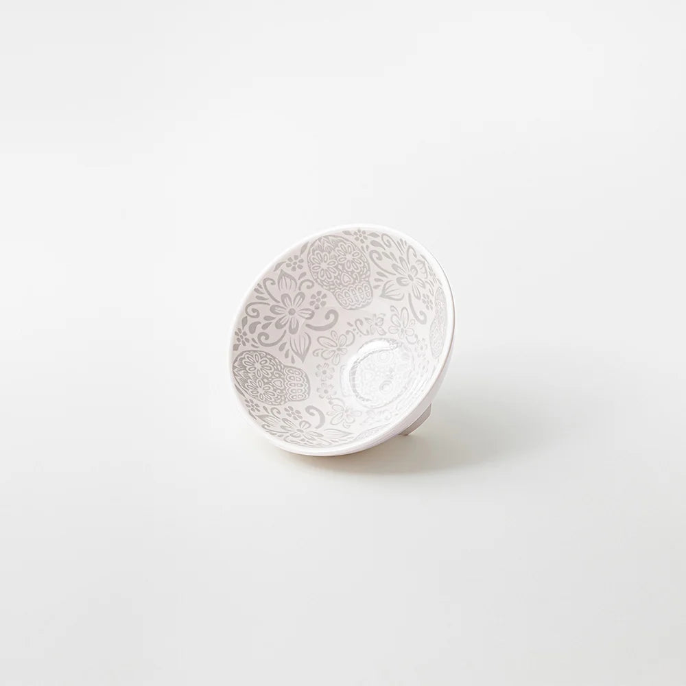 A small white ceramic bowl with delicate gray floral and paisley patterns on the inside, photographed on a seamless white background.