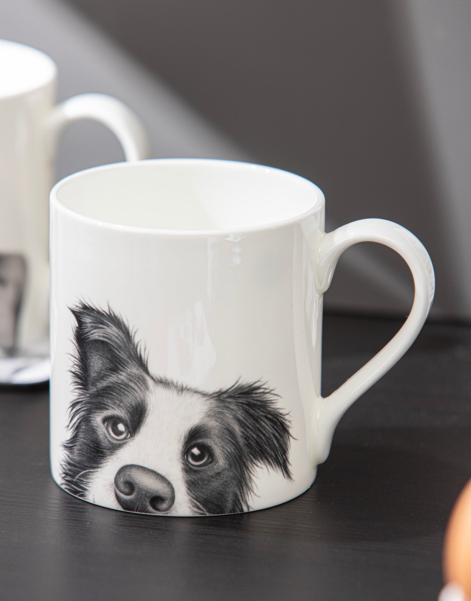 White mug with a black and white dog illustration on a dark surface