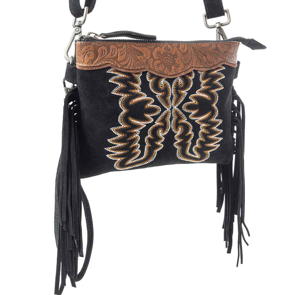 Desert Wing Crossbody Bag In Black. Black handbag with brown leather flap and embroidery on a white background
