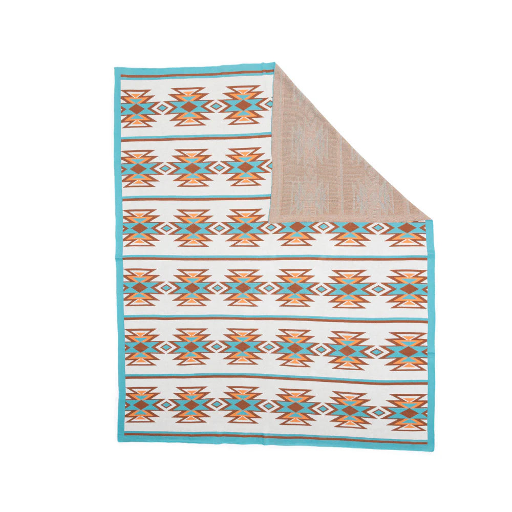 A cotton throw with turquoise and warm copper geometric patterns on a cream backdrop.