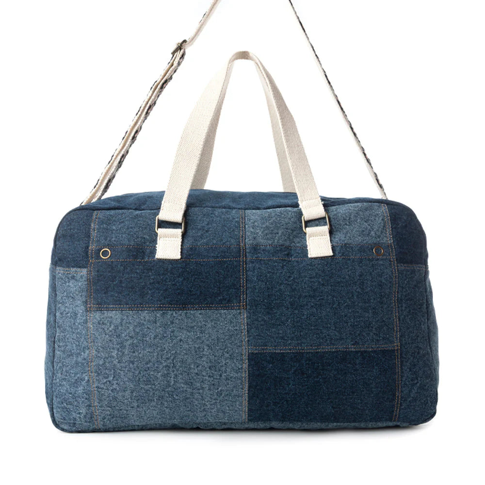 Blue patchwork duffel bag with white straps on a white background