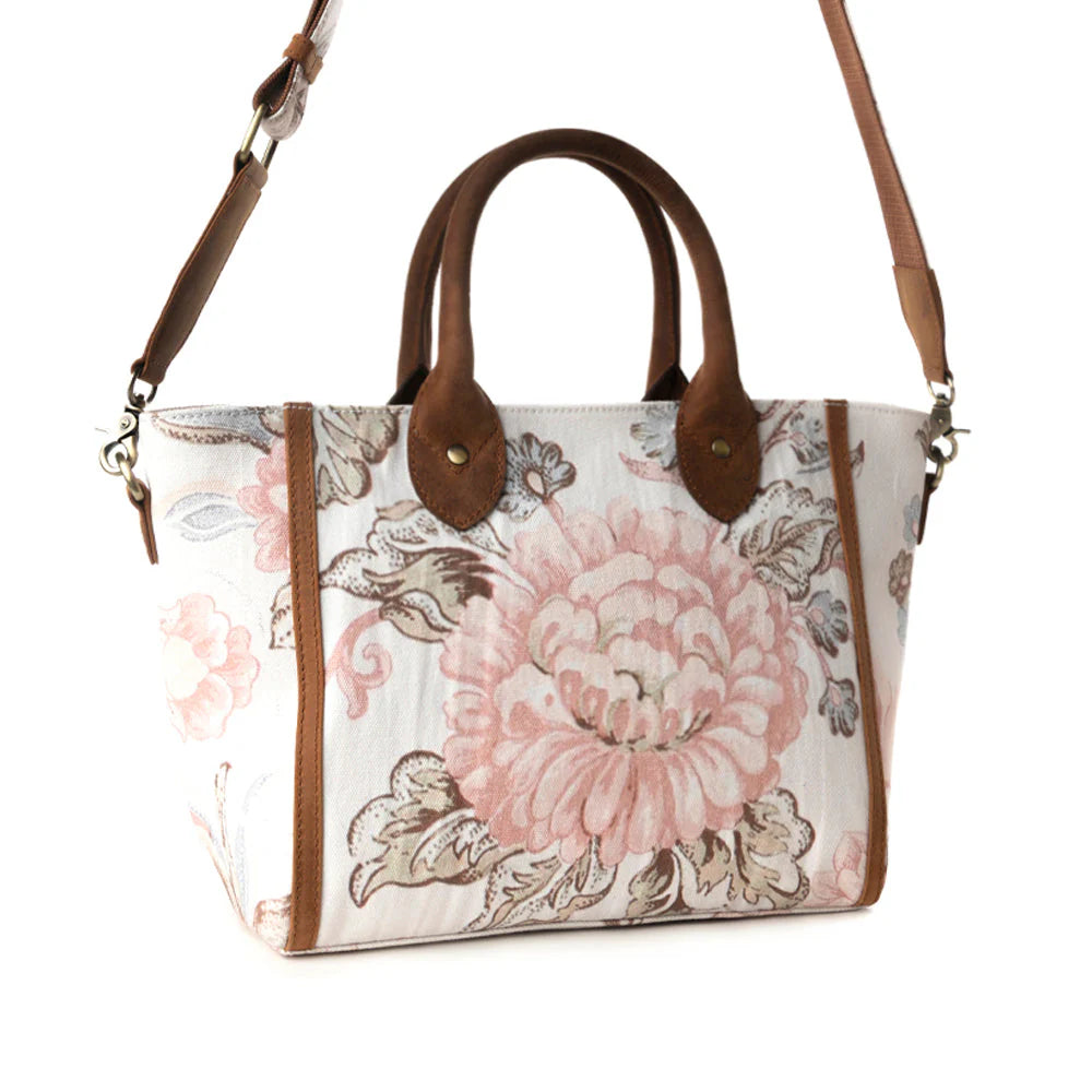 Floral patterned handbag with brown leather accents on a white background
